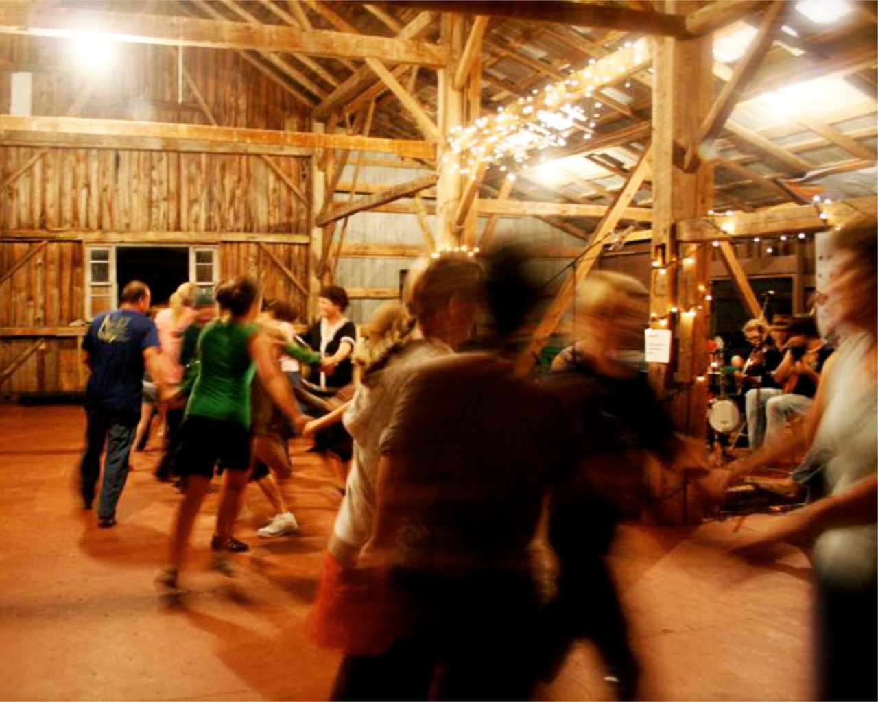 background photo people contradancing in old barn under warm lights